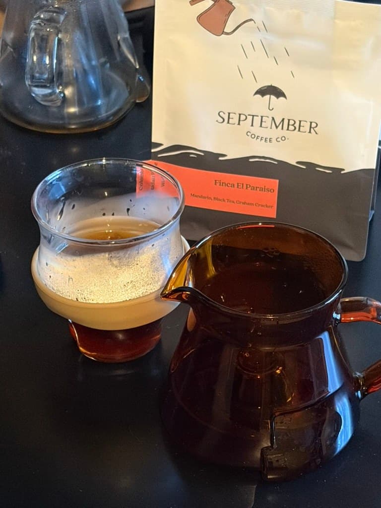 taza y server de vidrio con café filtrado junto a una bolsa de café